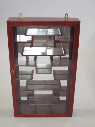 An Oriental hardwood hanging display cabinet with mirrored  back, fitted shelves enclosed by a glazed panelled door 18"
