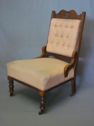 An Edwardian carved walnut nursing chair upholstered in cream material, raised on turned supports