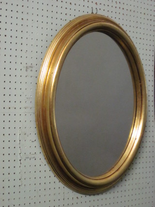 An oval plate mirror contained in a decorative gilt frame 23"
