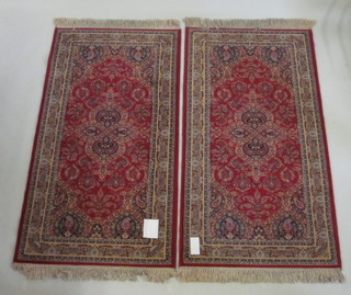 A pair of machine made red ground Persian rugs 69" x 36"