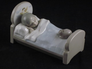 A Spanish porcelain figure of a sleeping child in bed with dog 5 1/2"