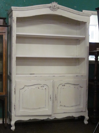 A French white painted arch shaped bookcase, the upper section  with adjustable shelves, the base fitted cupboards enclosed by  panelled doors, raised on cabriole supports 51"