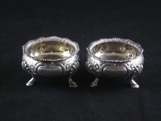 A pair of Victorian circular silver salts with embossed bodies, raised on hoof supports, London 1859, 5 1/2 ozs
