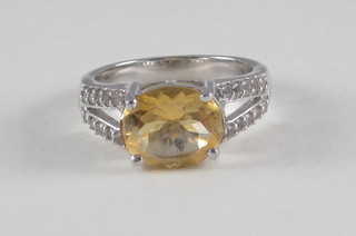A white gold dress ring set an oval topaz surrounded by  diamonds