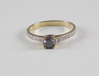A gold dress ring set a black diamond supported by white  diamonds