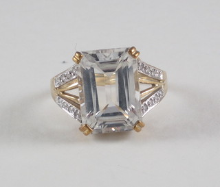 A lady's 9ct gold dress ring set a rectangular white coloured stone supported by diamonds to the shoulders