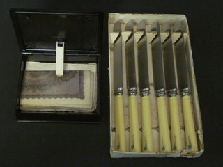 A Bakelite box containing 2 1000 mark notes and 6 Art Deco tea knives