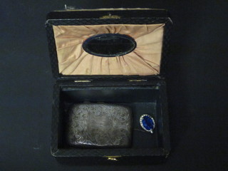 A leather jewellery box with hinged lid containing a blue glass pendant and a silver cheroot case