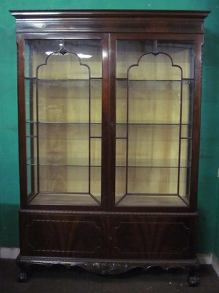 An Edwardian Chippendale style display cabinet with moulded  cornice, fitted shelves enclosed by astragal glazed panelled doors,  the base fitted cupboards enclosed by panelled doors, raised on  cabriole ball and claw supports 50"