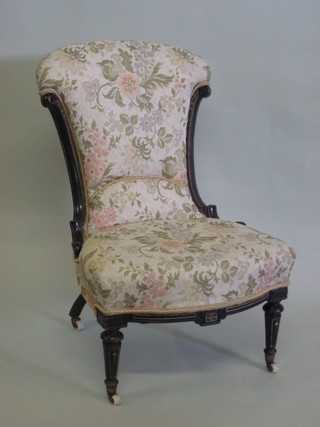 A Victorian ebonised nursing chair with floral patterned upholstered seat and back