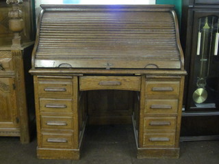 A honey oak kneehole pedestal roll top desk, the upper section  with well fitted interior, the base fitted 1 drawer flanked by  pedestals fitted brushing slides and 8 short drawers 48"