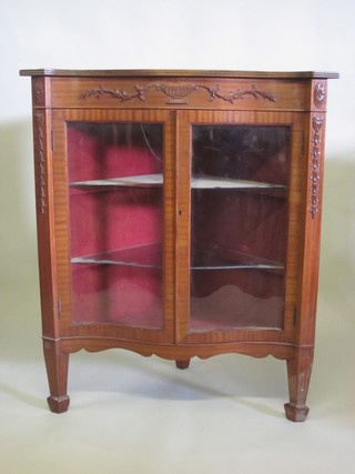 A Georgian style mahogany corner cabinet of serpentine outline, the interior fitted shelves enclosed by glazed panelled doors,  raised on square supports 38"
