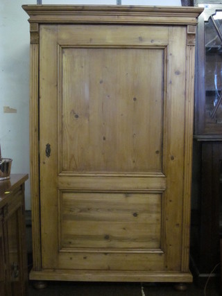A Continental stripped and polished pine cupboard with moulded cornice, fitted shelves enclosed by a panelled door, raised on bun  feet 41"