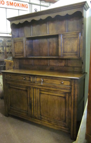 A carved oak dresser with raised back fitted 2 cupboards, the  base fitted 2 drawers above a double cupboard 54"