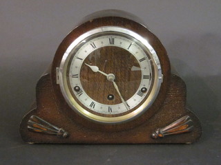 A chiming mantel clock with silvered dial and Roman numerals contained in an oak arch shaped case