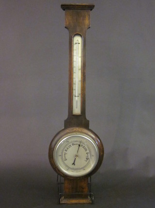 An aneroid barometer with silvered dial contained in an oak wheel case