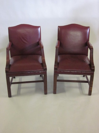 A pair of Georgian style mahogany open arm library chairs with leather upholstered seats and backs