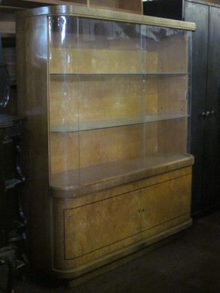 An Art Deco D shaped Continental walnut display cabinet fitted shelves enclosed by glazed sliding panelled doors, the base fitted  a double cupboard 53"