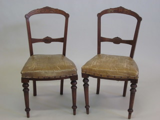 A pair of Edwardian rail back dining chairs with carved mid rails  and upholstered seats