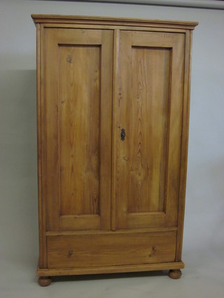 A stripped and polished pine cupboard, the interior fitted shelves enclosed by a panelled door, the base fitted 1 long drawer and  raised on bun feet 41"