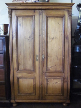 A pine cupboard with moulded cornice, fitted shelves enclosed by panelled doors 42", raised on bun feet