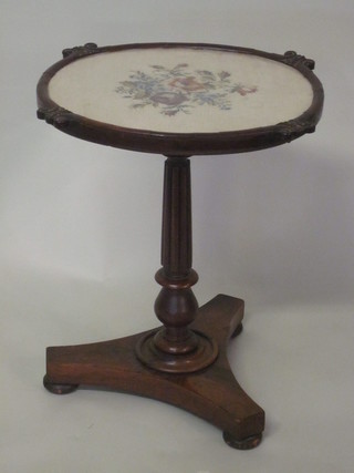 A William IV mahogany occasional table formed from a pole  screen with oval Berlin woolwork banner, raised on turned and  reeded supports with triform base 16"