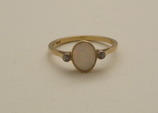 An 18ct gold dress ring set a small oval opal supported by 2  diamonds