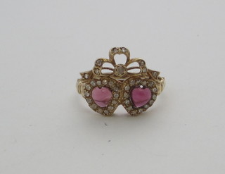 An 18ct gold dress ring in the form of 2 entwined hearts set cabouchon cut garnets supported by diamonds