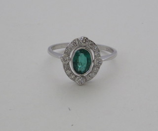 A lady's 18ct white gold dress ring set an oval cut emerald  surrounded by diamonds approx 0.40/0.50ct