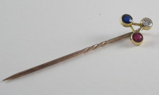 A gold triangular shaped stick pin set a diamond, sapphire and  ruby