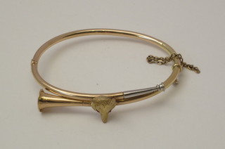 A gilt metal bangle in the form of a French horn set a foxes mask