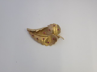 A gold brooch in the form of a leaf set red stones