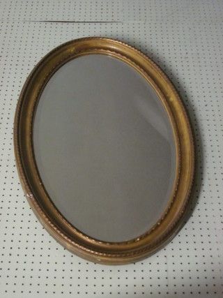 An oval bevelled plate wall mirror contained in a decorative gilt  frame 31"