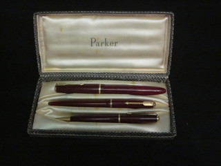 A red Parker Duofold fountain pen, top f, a red Parker ballpoint pen marked Regtm6 and a red Parker propelling pencil