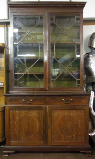 A Chippendale style mahogany bookcase on cabinet, the upper section with moulded and dentil cornice fitted adjustable shelves  enclosed by astragal glazed panelled doors, the base fitted 1 long  drawer with cupboard fitted 2 short drawers enclosed by panelled  doors, raised on ogee bracket feet 47"
