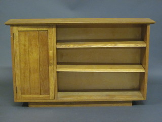A honey oak bookcase fitted adjustable shelves and with cupboard to the side enclosed by a panelled door 46"