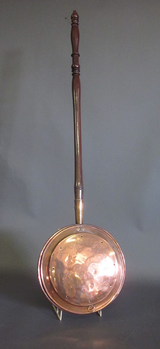 An 18th Century copper warming pan with turned fruitwood  handle