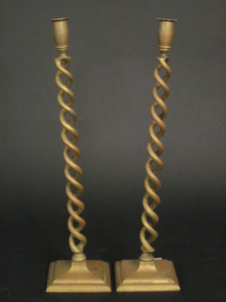 A pair of brass spiral turned candlesticks, raised on square bases 21"