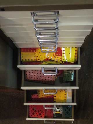 A brown and white painted filing chest fitted 15 shallow drawers  containing a collection of red, yellow and blue Meccano