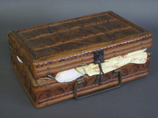 A small bamboo case containing a collection of dolls clothes and christening gowns