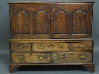 An 18th Century carved oak mule chest, converted to a cabinet, having arch shaped panelled doors above 2 short and 3 long  drawers, 55"  ILLUSTRATED