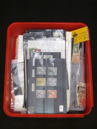 A red plastic biscuit tin containing a good collection of stamps