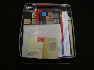 A metal biscuit tin containing a collection of various stamps