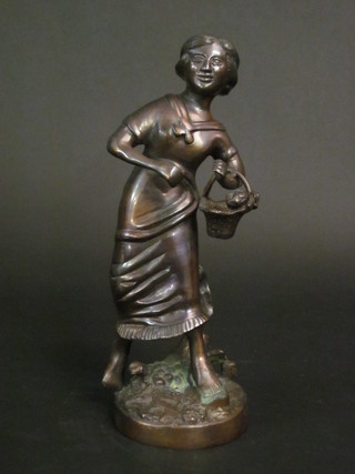A bronze figure of a standing girl with basket