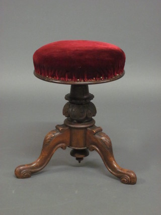 A Victorian carved walnut adjustable piano stool, raised on a tripod base
