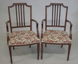A pair of mahogany stick and rail back Hepplewhite style open arm carver chairs with upholstered seats, raised on square  tapering supports ending in spade feet