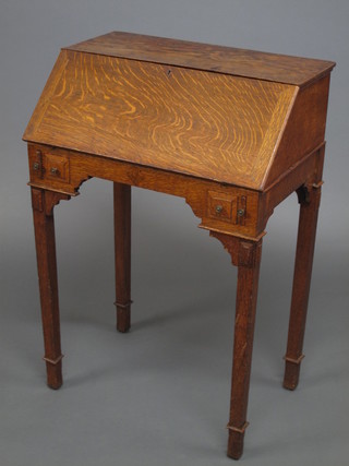 A lady's oak bureau with fall front above 2 short drawers, raised  on square tapering supports ending in spade feet 25"
