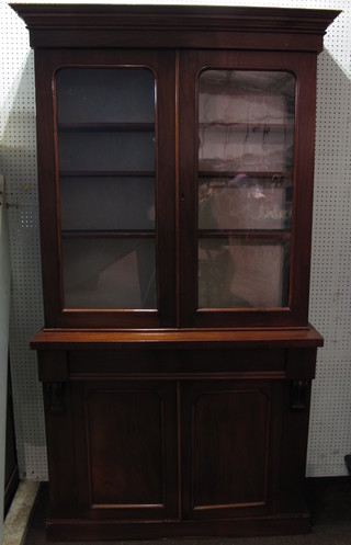 A Victorian mahogany bookcase on cabinet, the upper section  with moulded cornice the interior fitted adjustable shelves  enclosed by a pair of arched panelled doors, the base fitted 1 long  drawer above a double cupboard enclosed by an arch shaped  panelled door, raised on a platform base 44"