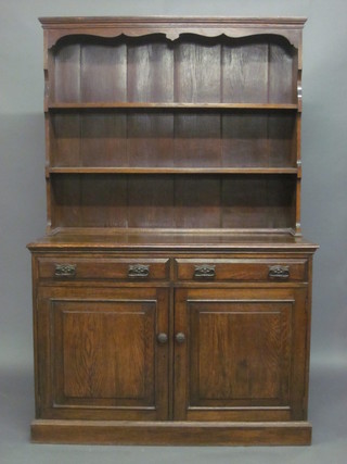 An Art Nouveau oak dresser with raised back, the base fitted 2 drawers with double cupboard, raised on a platform base 48"