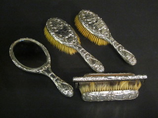A matched 6 piece embossed silver dressing table set comprising hand mirror, pair of clothes brushes, pair of hair brushes and  comb, decorated Angels